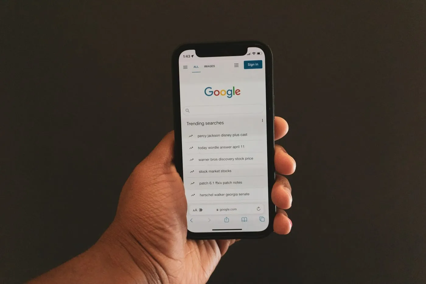 A hand holding a phone open to Google