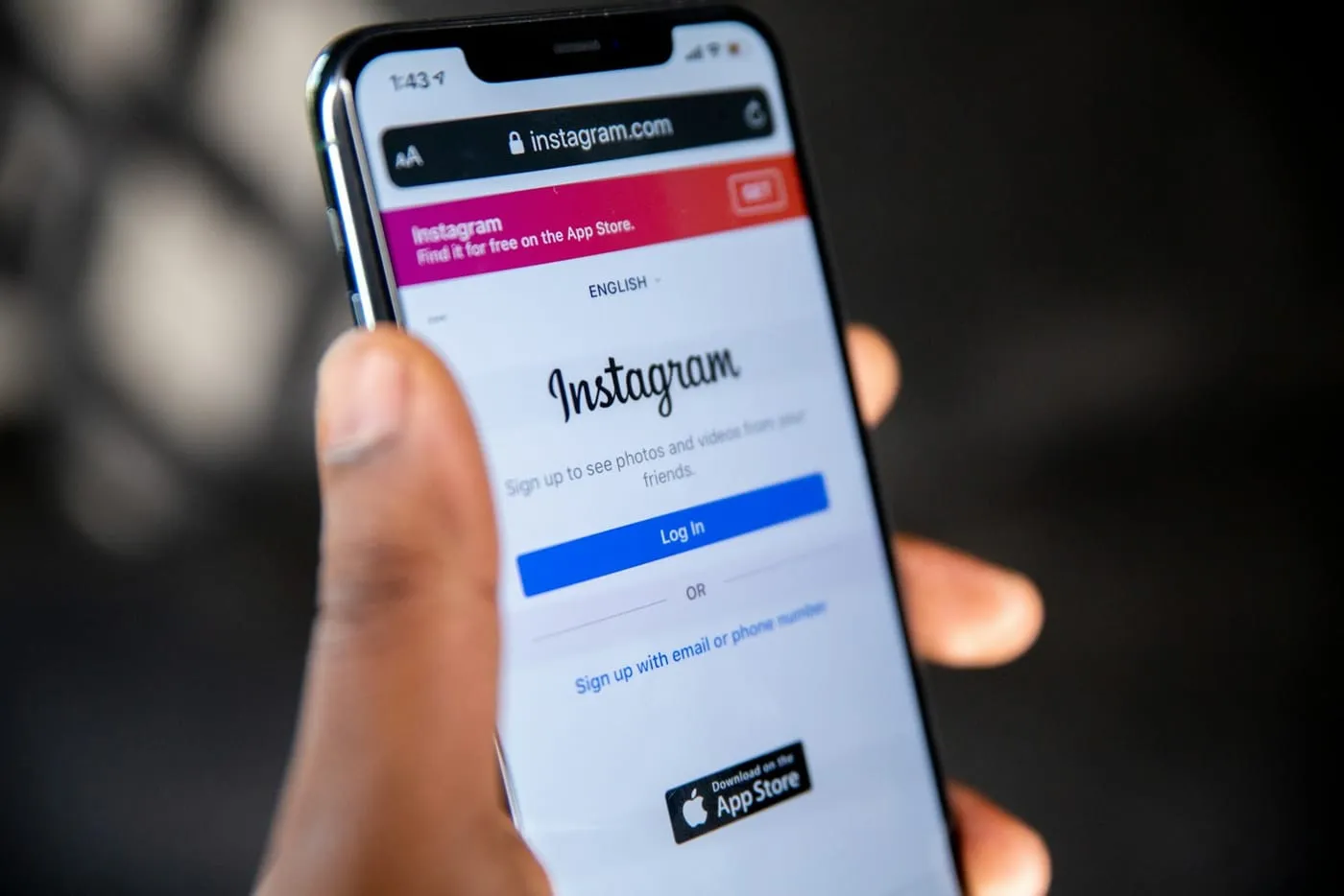 A hand holding a phone showing the Instagram login screen