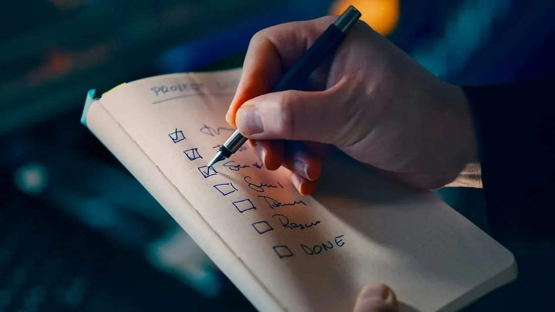 A hand ticking off a checklist in a notebook