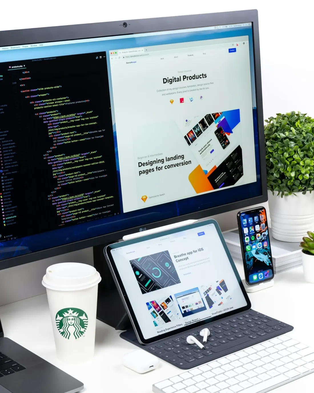 A desk with a monitor, tablet and phone showing website designs