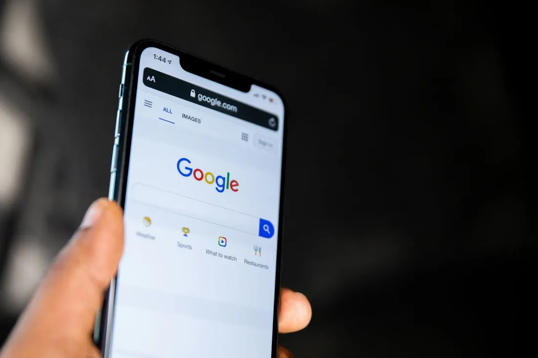 A hand holding a phone open to the Google search page
